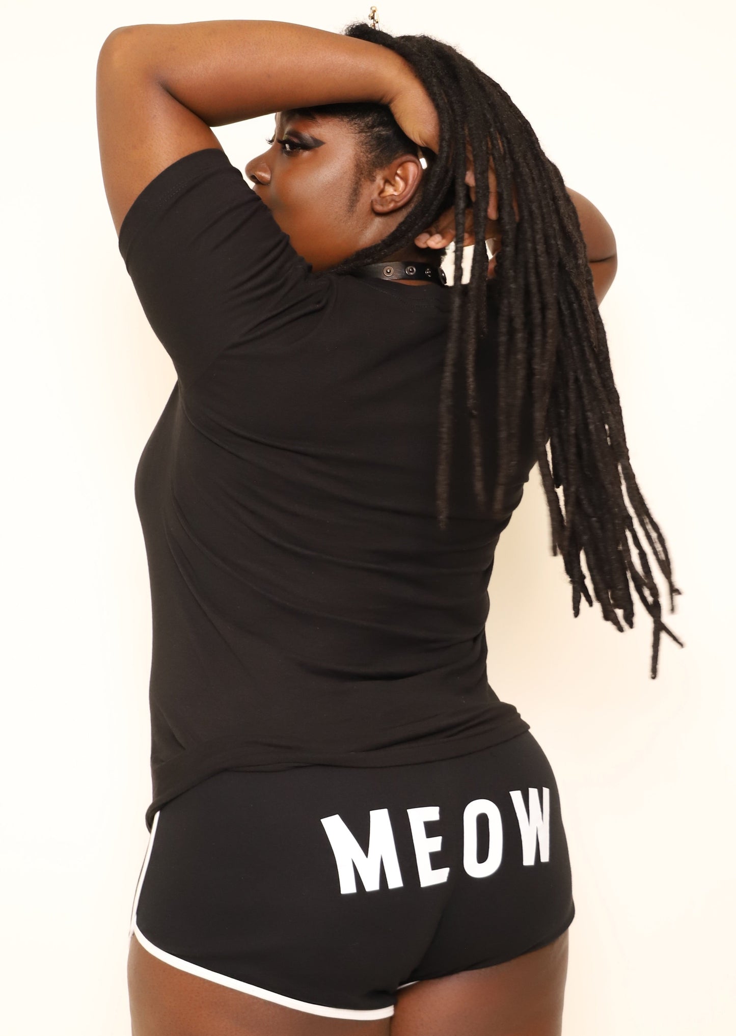 Person wearing a black t-shirt and shorts with 'MEOW' printed on the shorts